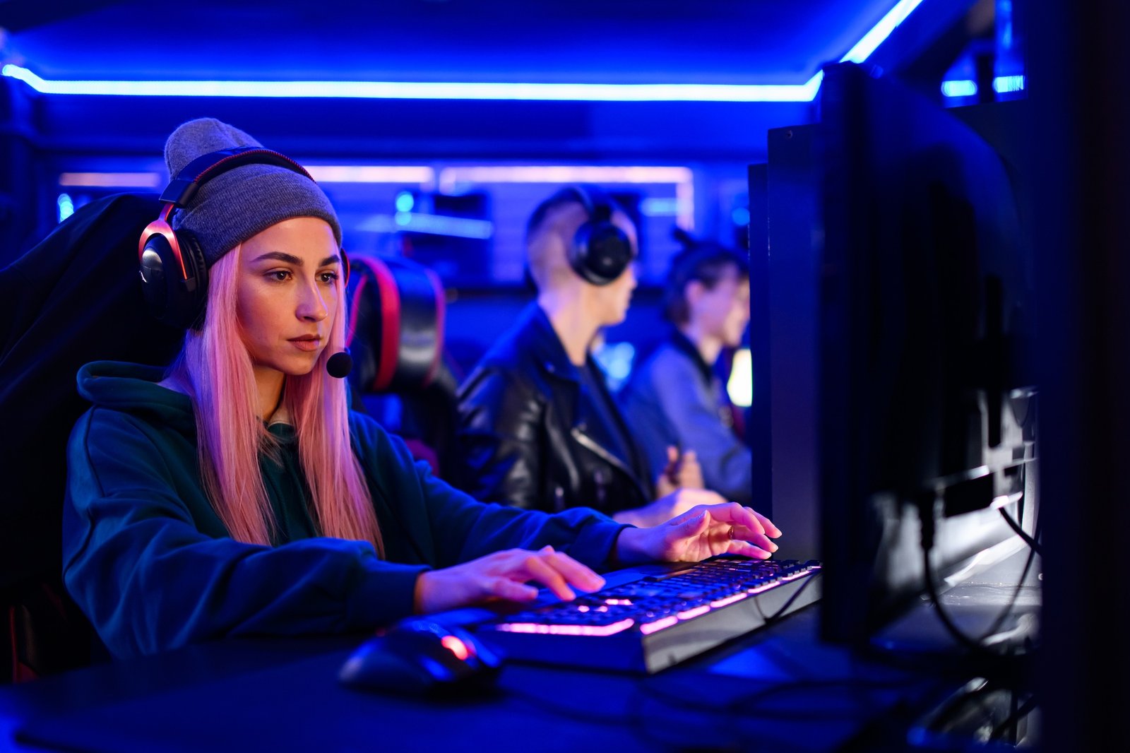 Gamer girl with headset sitting in neon lit cybercafe, playing mmo rpg